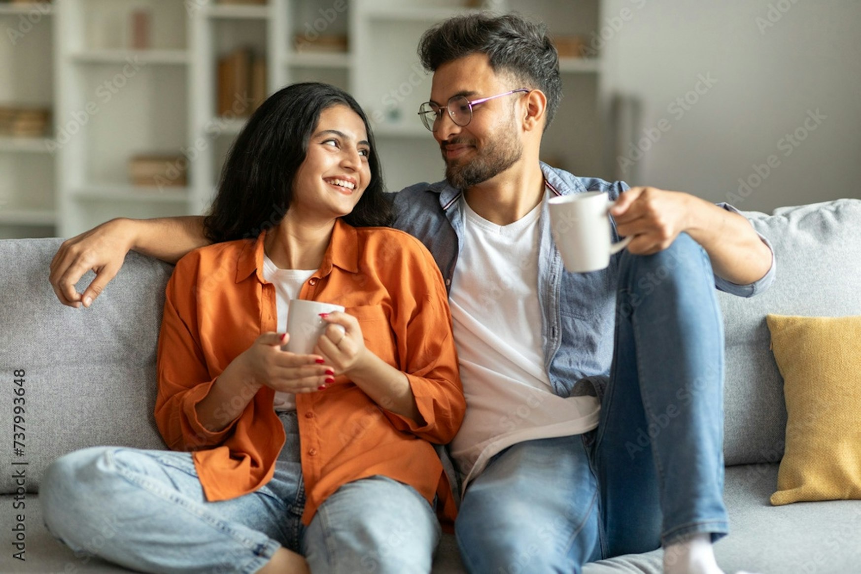 Couple sitting on a couch holding cups